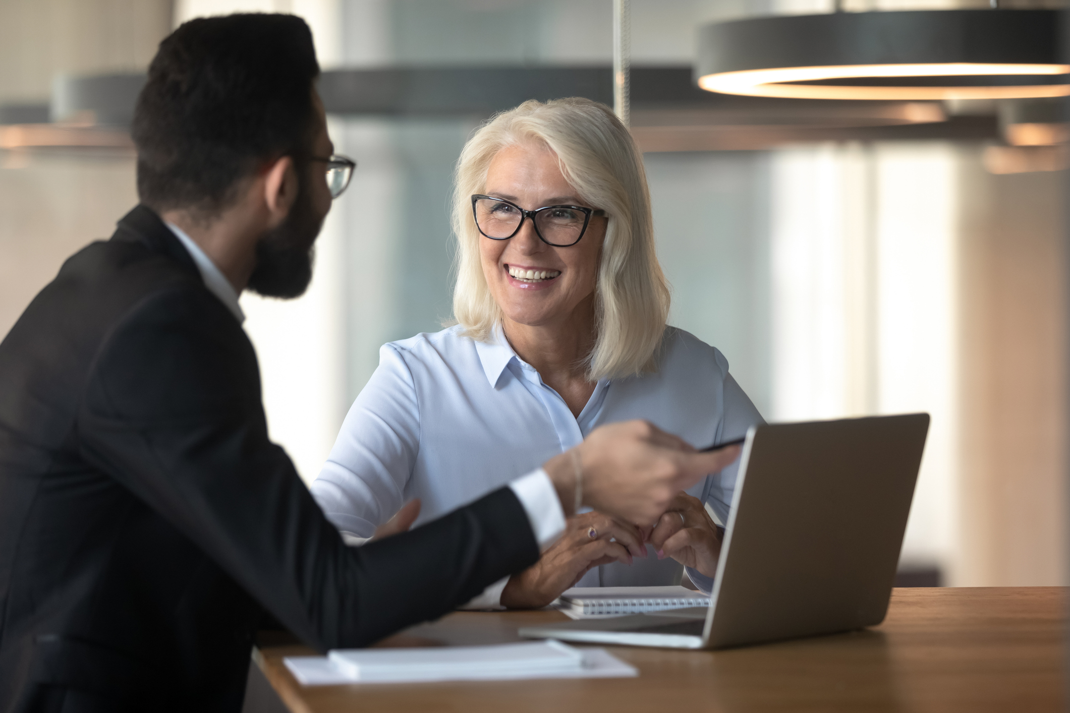 Photo of businessman consulting mature businesswoman client in an office.