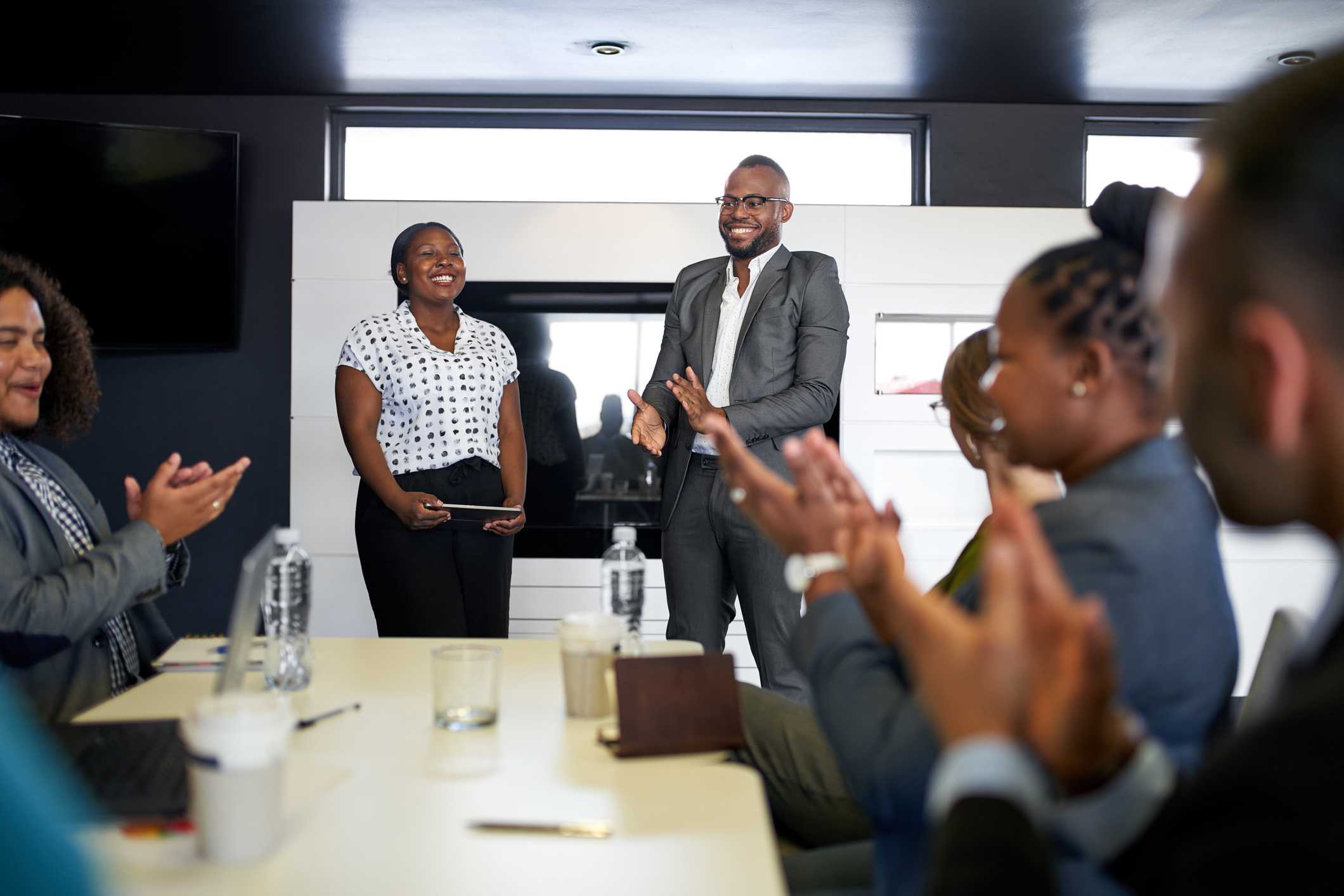 Photo of black businessman being encouraged by diverse multi-ethnic group of coworkers during presentation in office