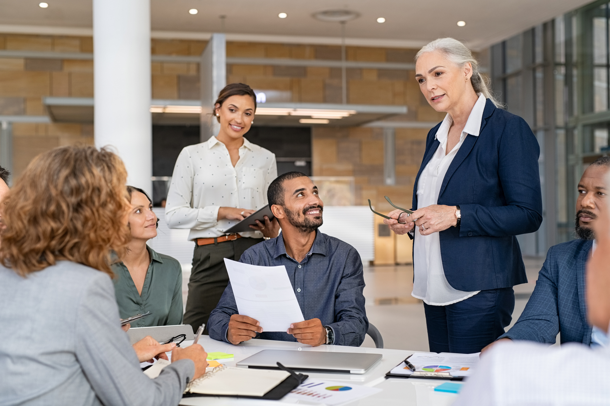 Photo of a senior business manager guiding employees in meeting.