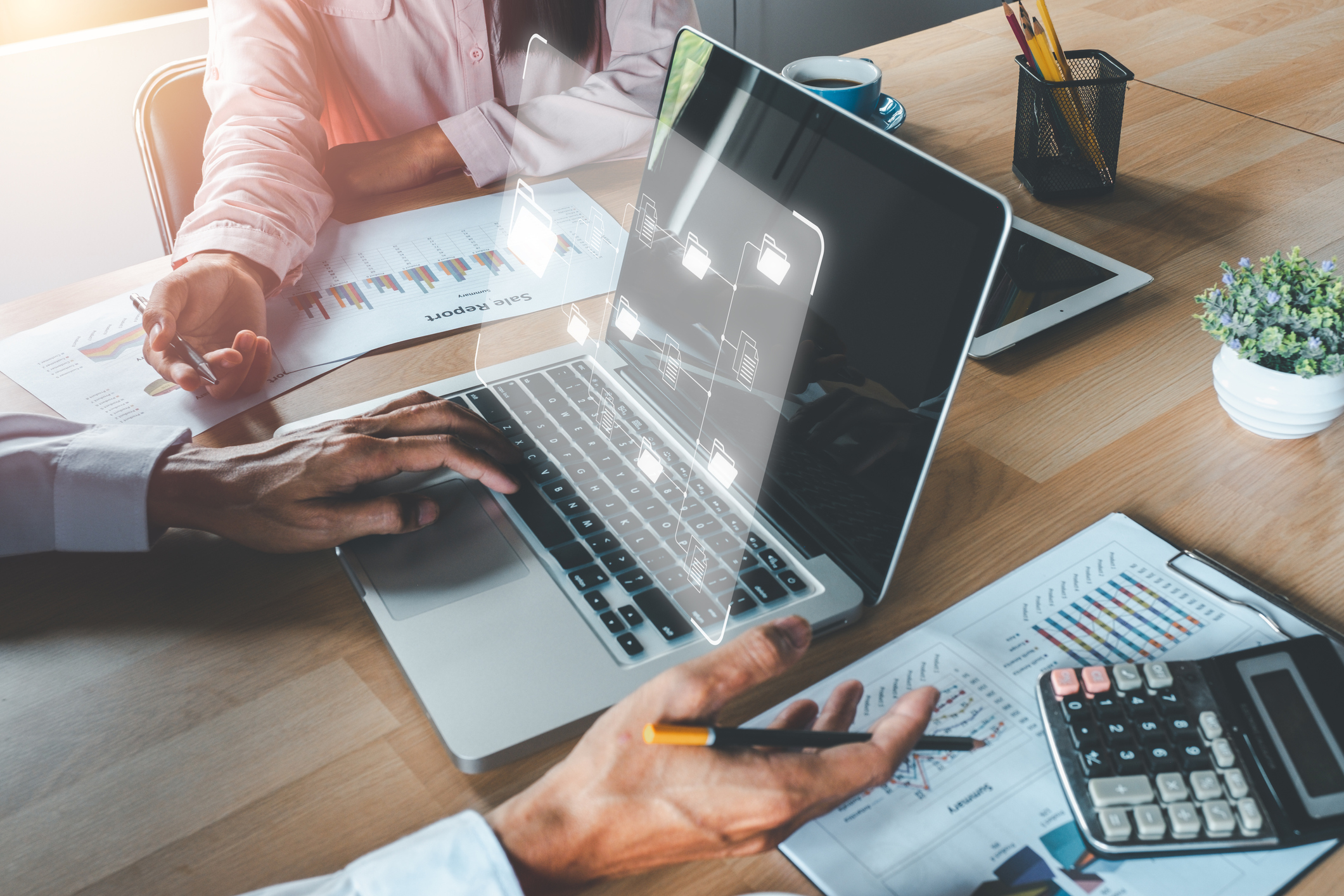 Photo of two people working at a laptop with business documents.