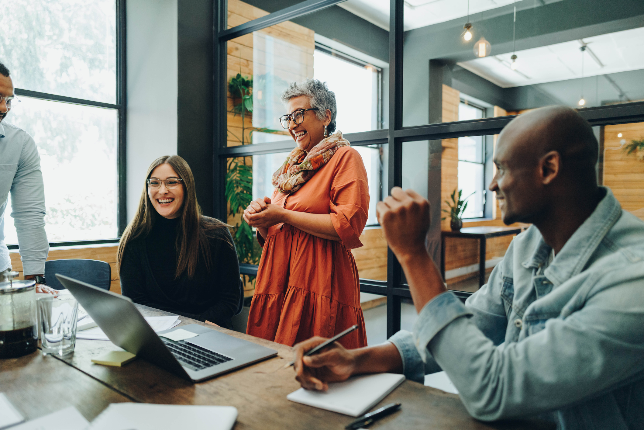 Photo of Diverse businesspeople smiling cheerfully during a meeting in a modern office. 