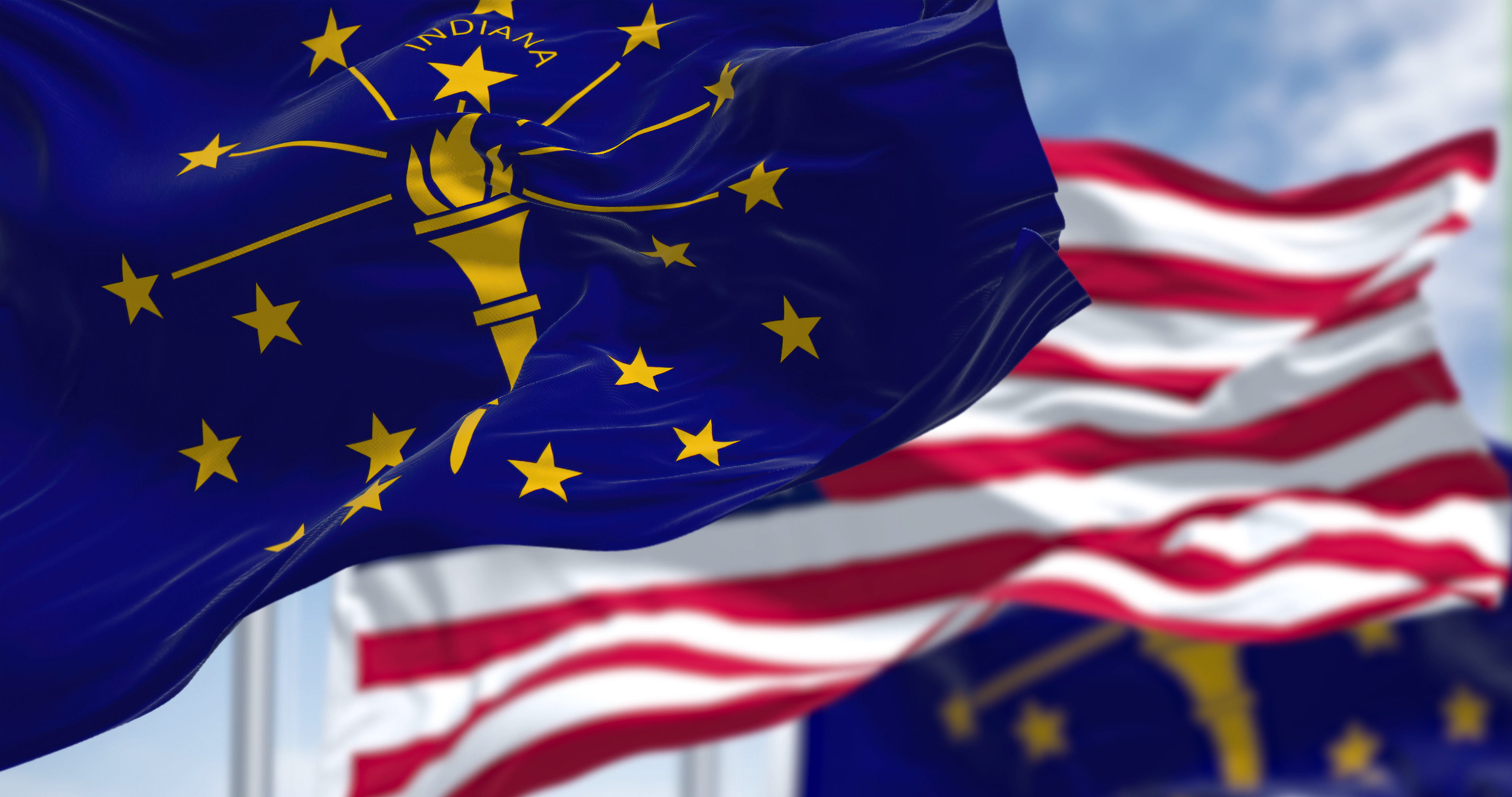 Photo of the Indiana state flag waving along with the national flag of the United States of America.