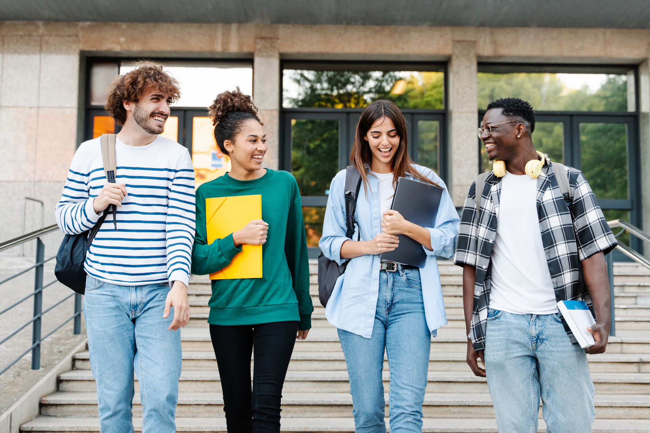 Photo of Happy students walking together on university campus, chatting and laughing outdoors after classes