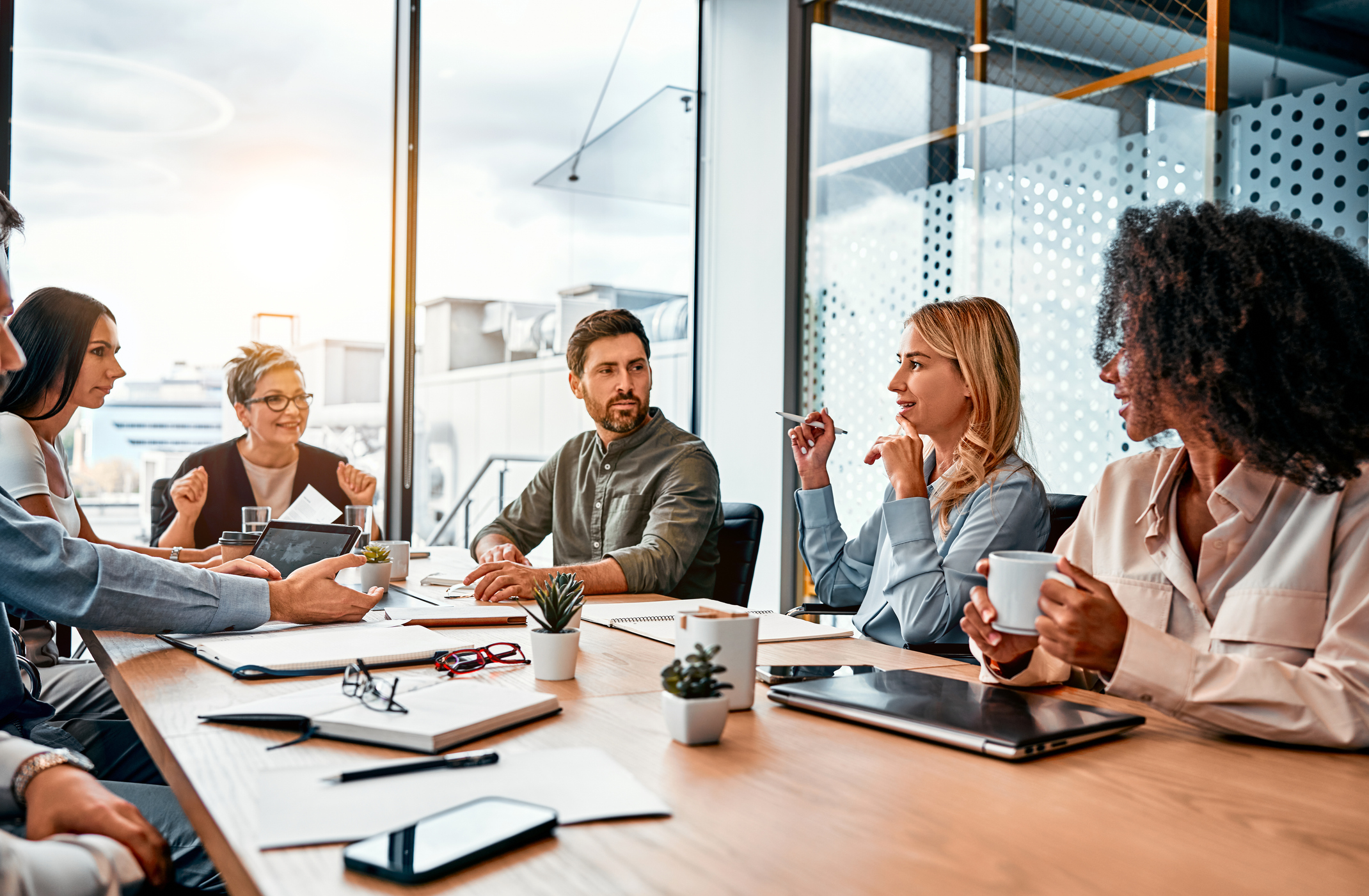 Multinational professionals business people discussing daily topics by table in modern office. Business meeting.