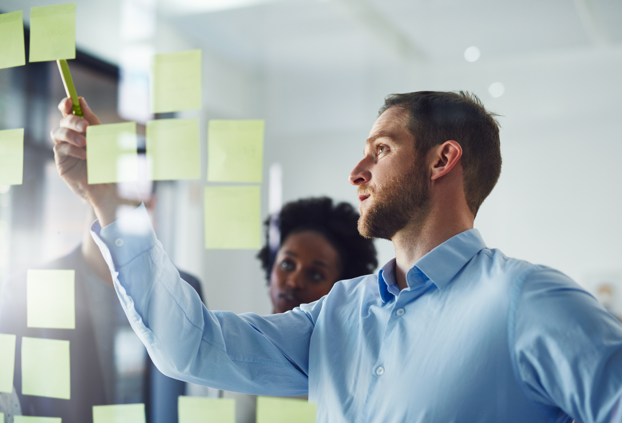 Cropped shot of a group of businesspeople working on a glass wall in the office