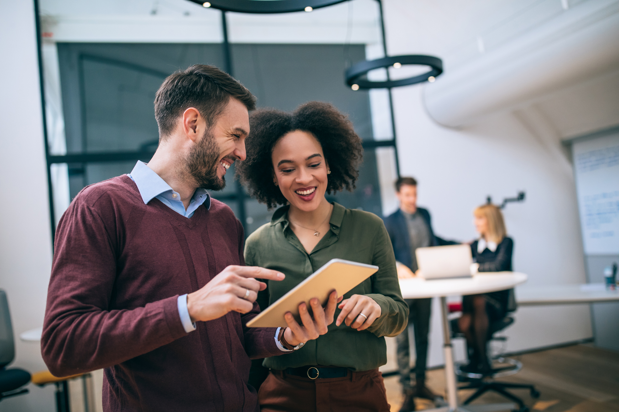 Photo of coworkers standing in an office, looking at a digital tablet